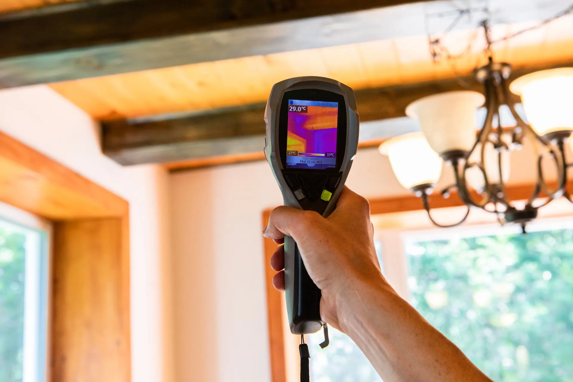 Person holding a thermal imaging camera indoors.