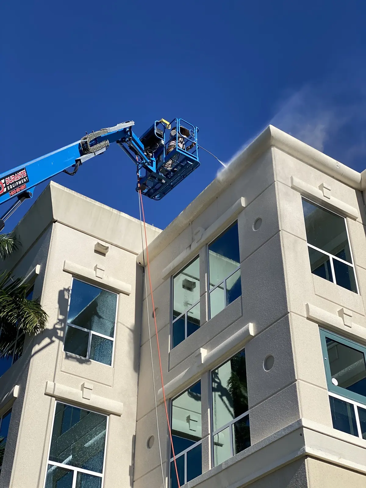 Worker on a lift cleaning windows of a modern building.
